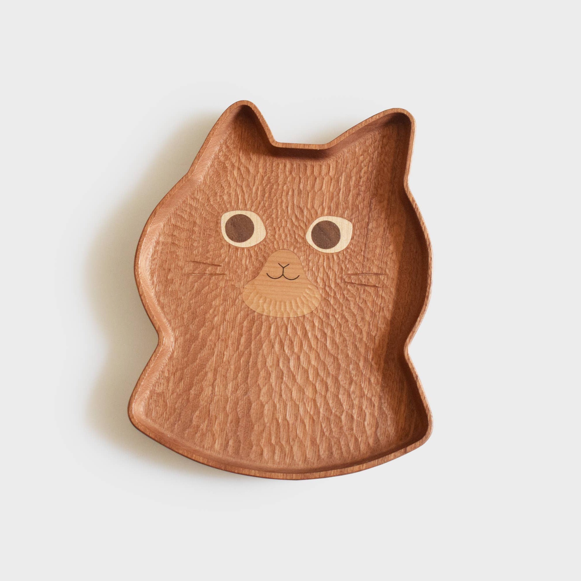 Cat-shaped wooden plate on a light beige background