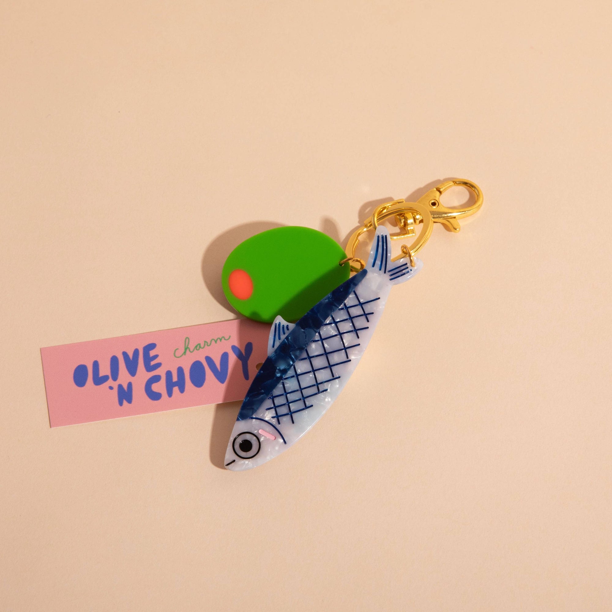 Keychain with green olive and pink label on beige background