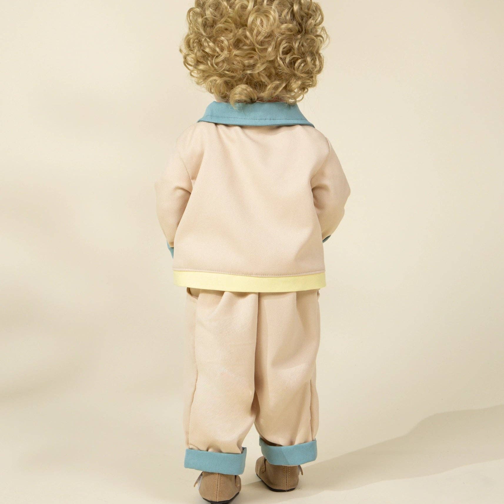 doll wearing a beige outfit with blue accents on a beige background