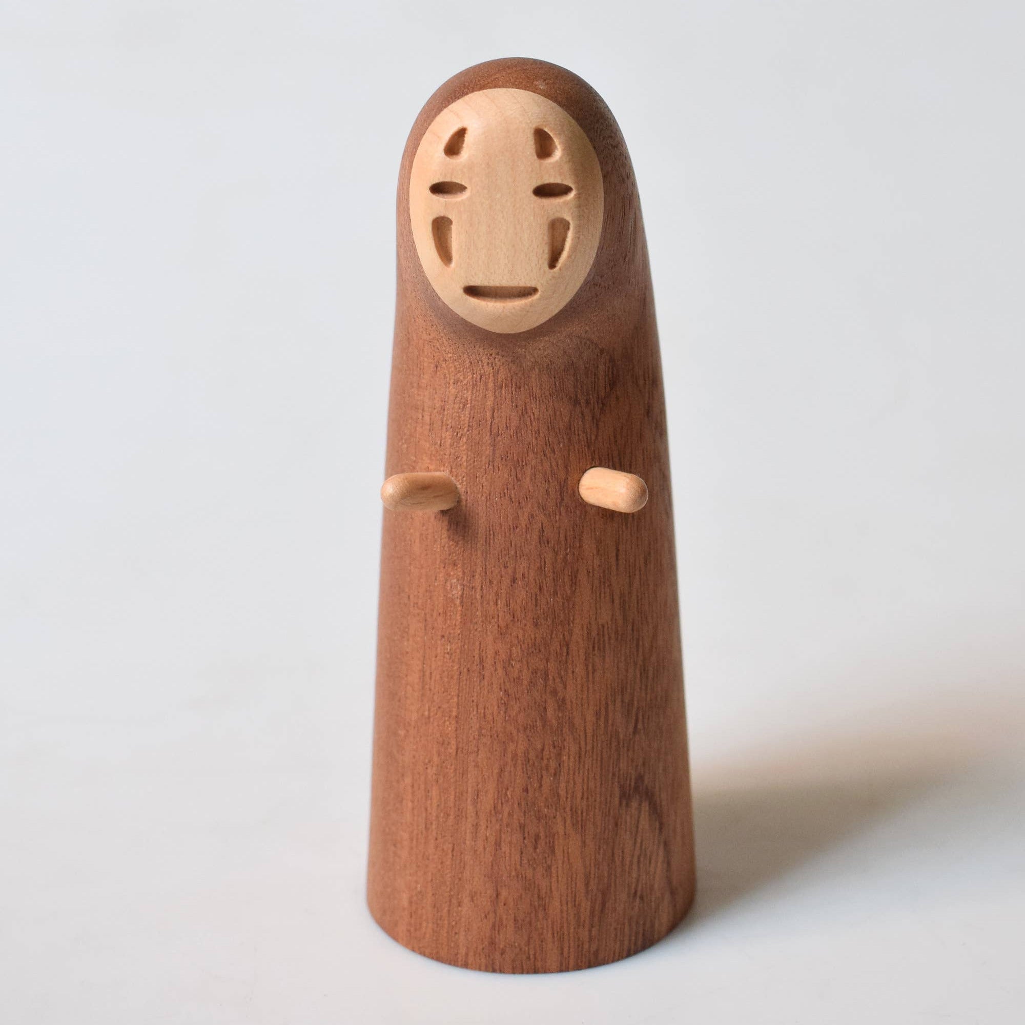 Wooden figurine with a minimalist face on a white background