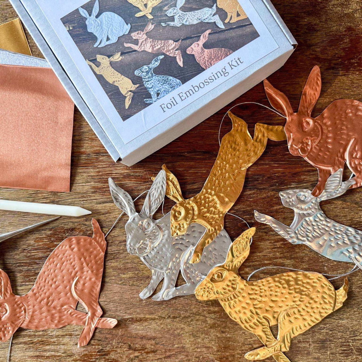 Foil embossing kit with rabbit designs on a wooden surface