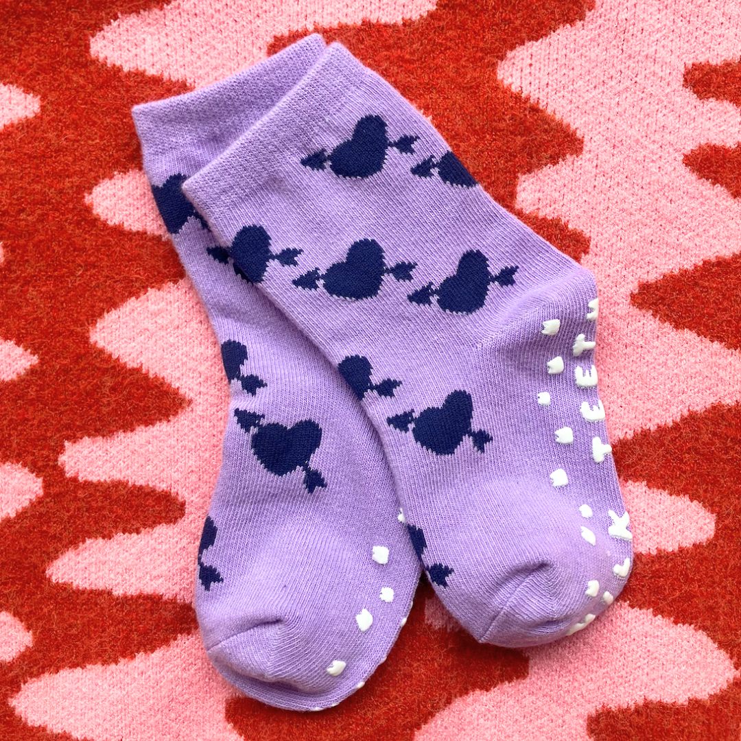 Purple socks with blue hearts on a red and pink patterned surface