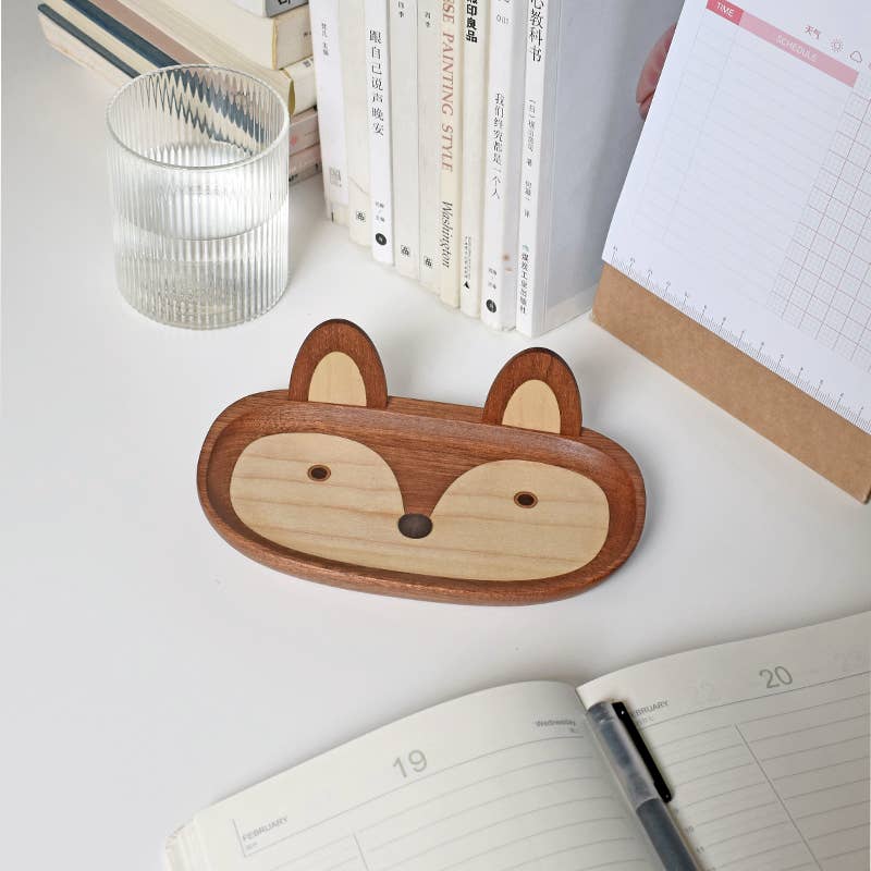 Wooden fox-shaped tray on a desk with books and a notebook in the background