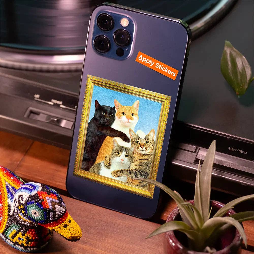 Phone case with cat illustration on a desk with a laptop and plant