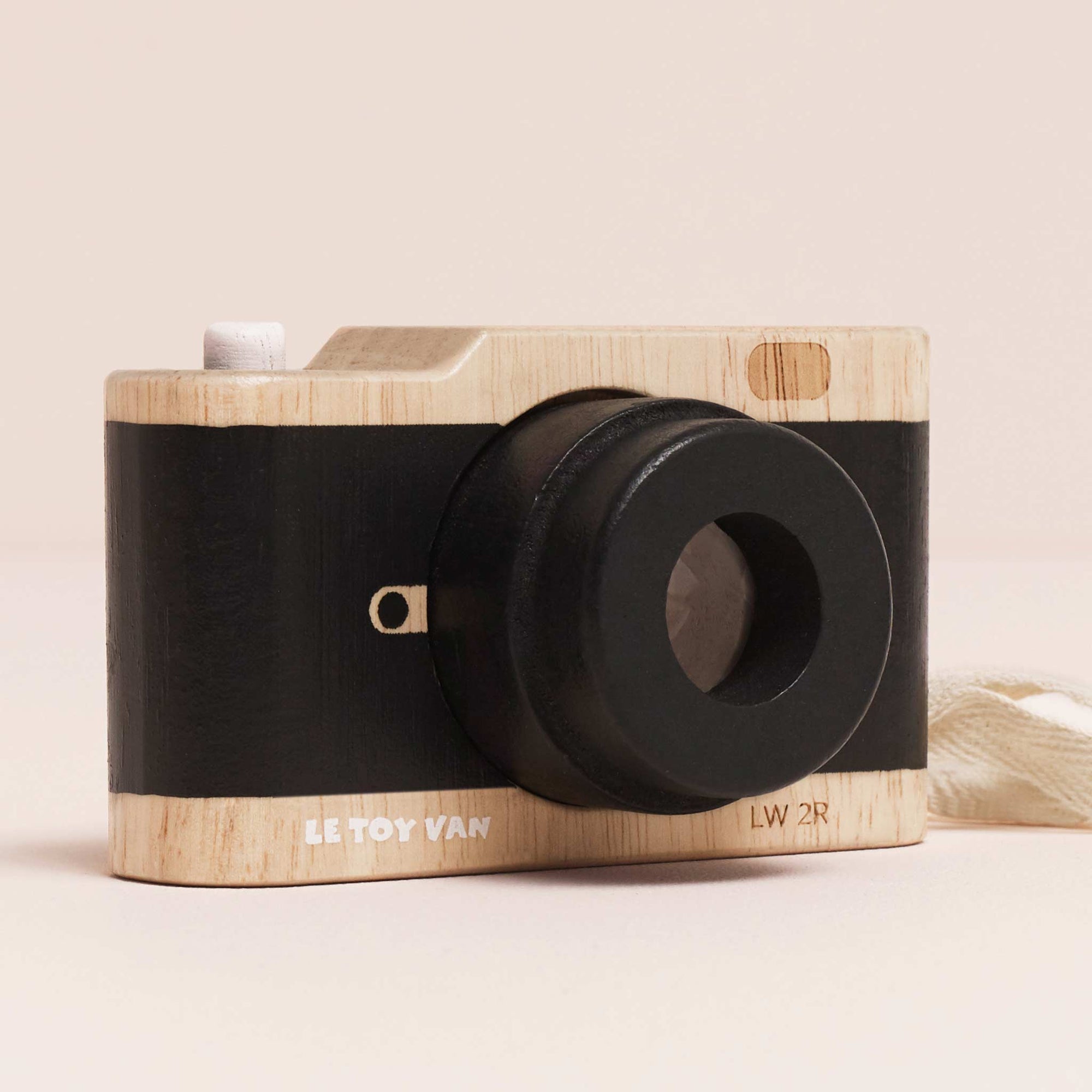 Wooden toy camera with black lens on a beige background
