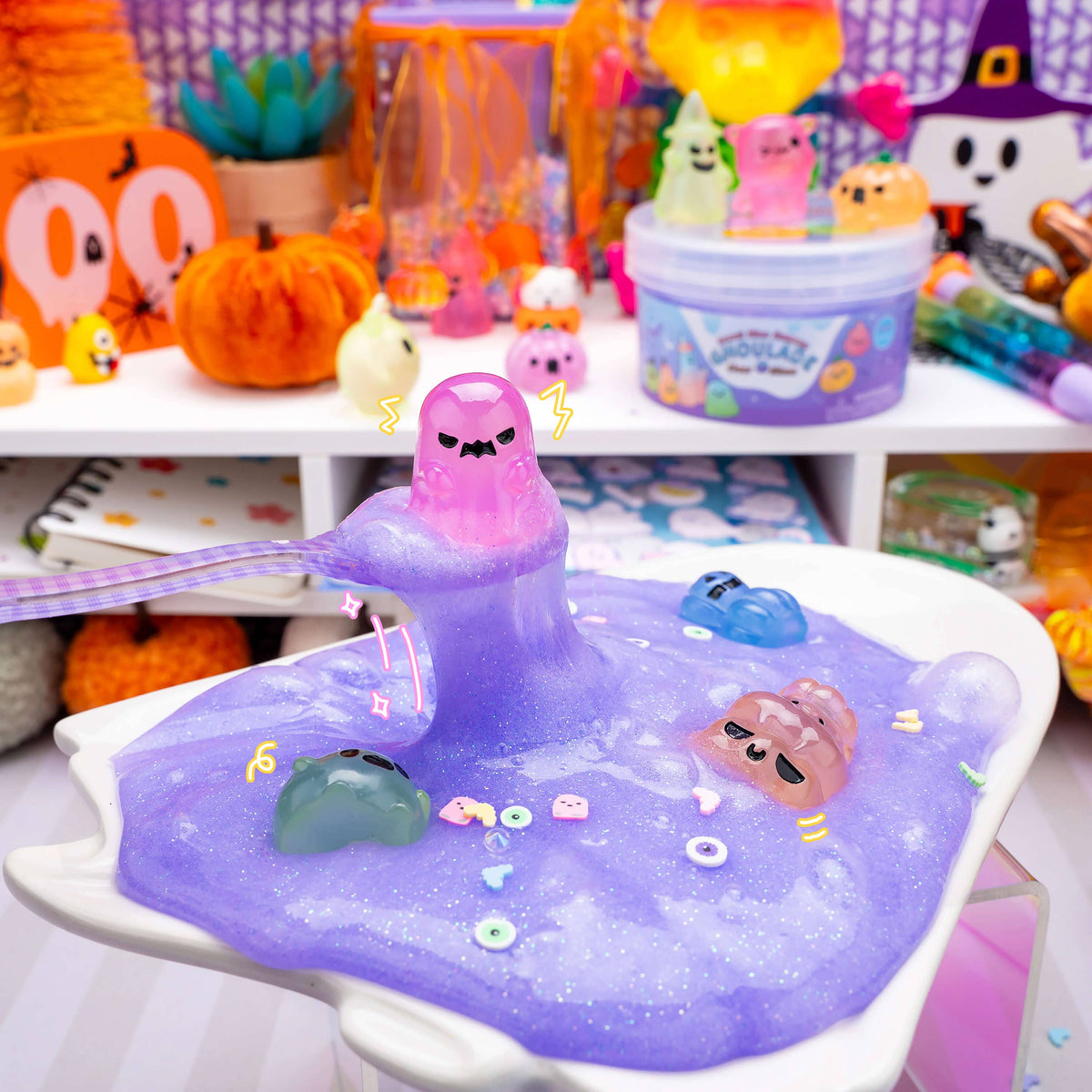 Purple slime toy with cartoon characters on a white tray, surrounded by Halloween-themed decorations.