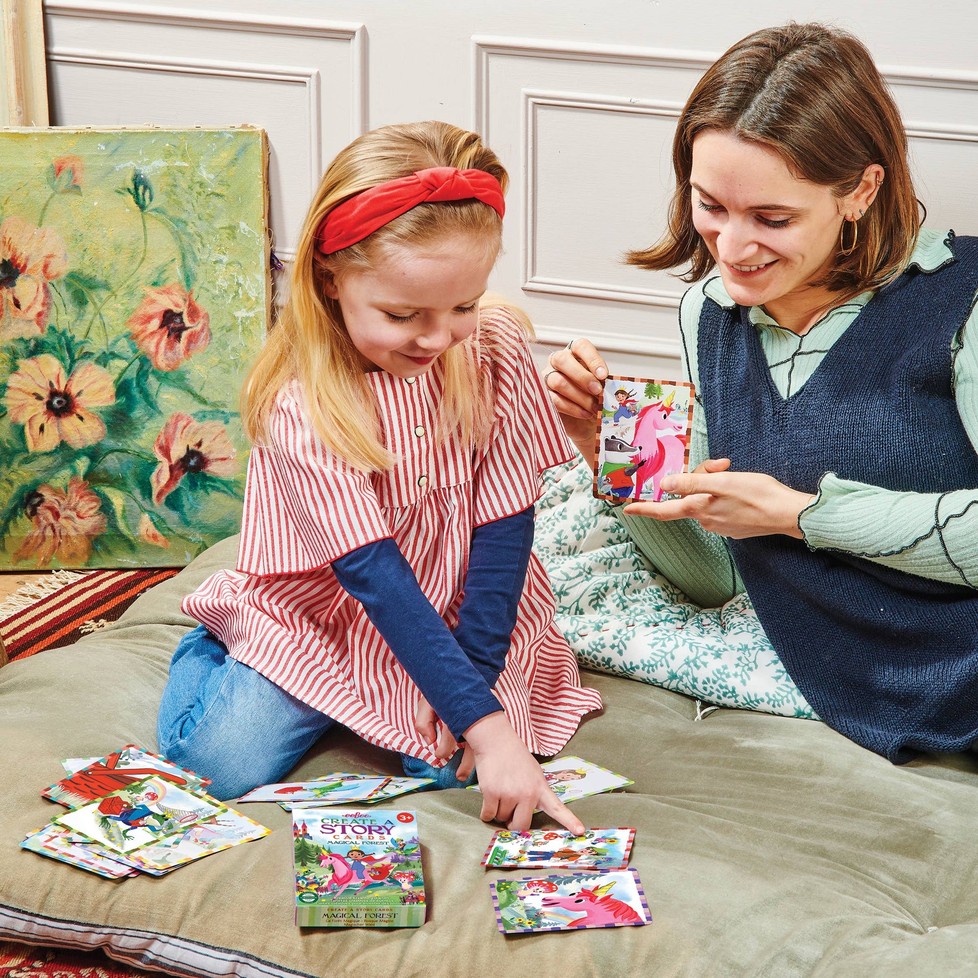 Woman and young girl playing with colorful storybooks on a bed