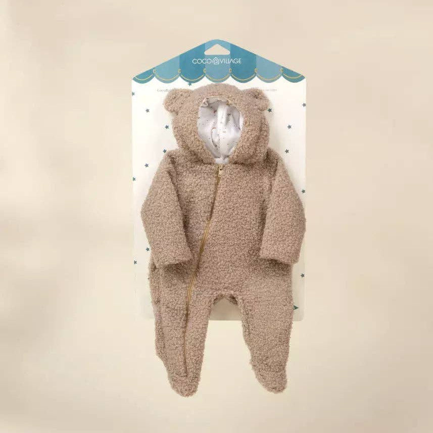 A baby teddy bear footed onesie in a warm taupe-brown color, displayed on its white and blue retail card packaging against a solid beige background.