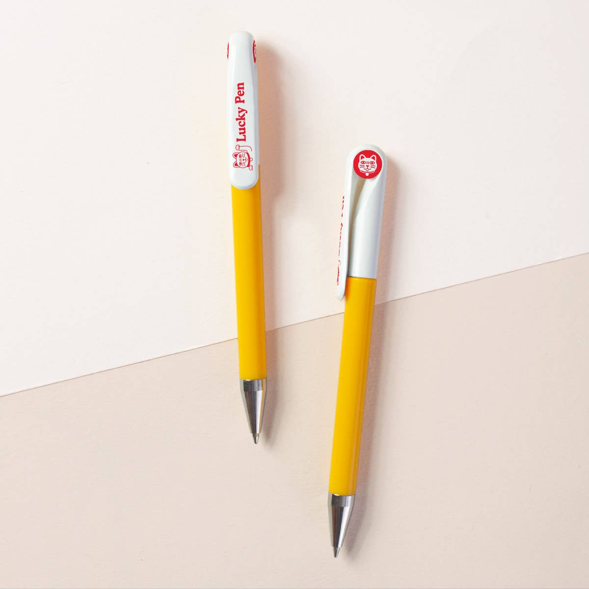 Two yellow pens with silver accents on a light background