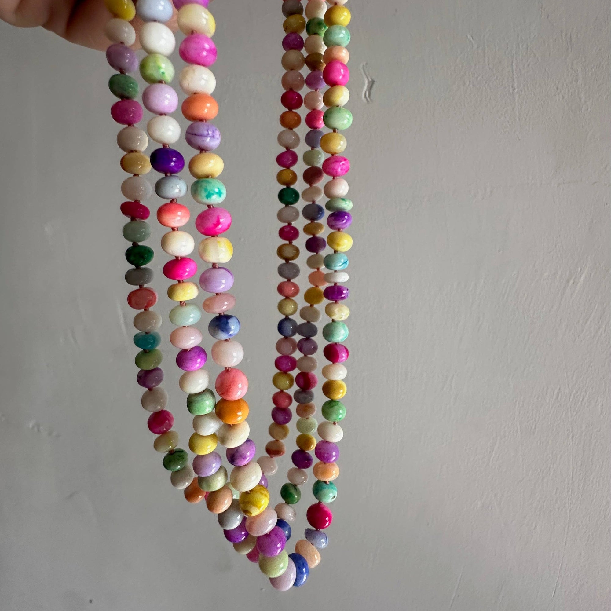 Colorful beaded necklace held against a plain background