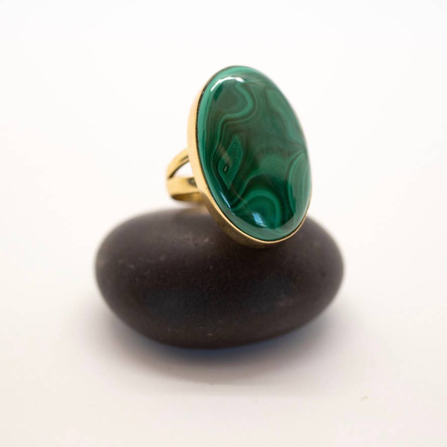 Gold ring with a green stone on a dark stone surface