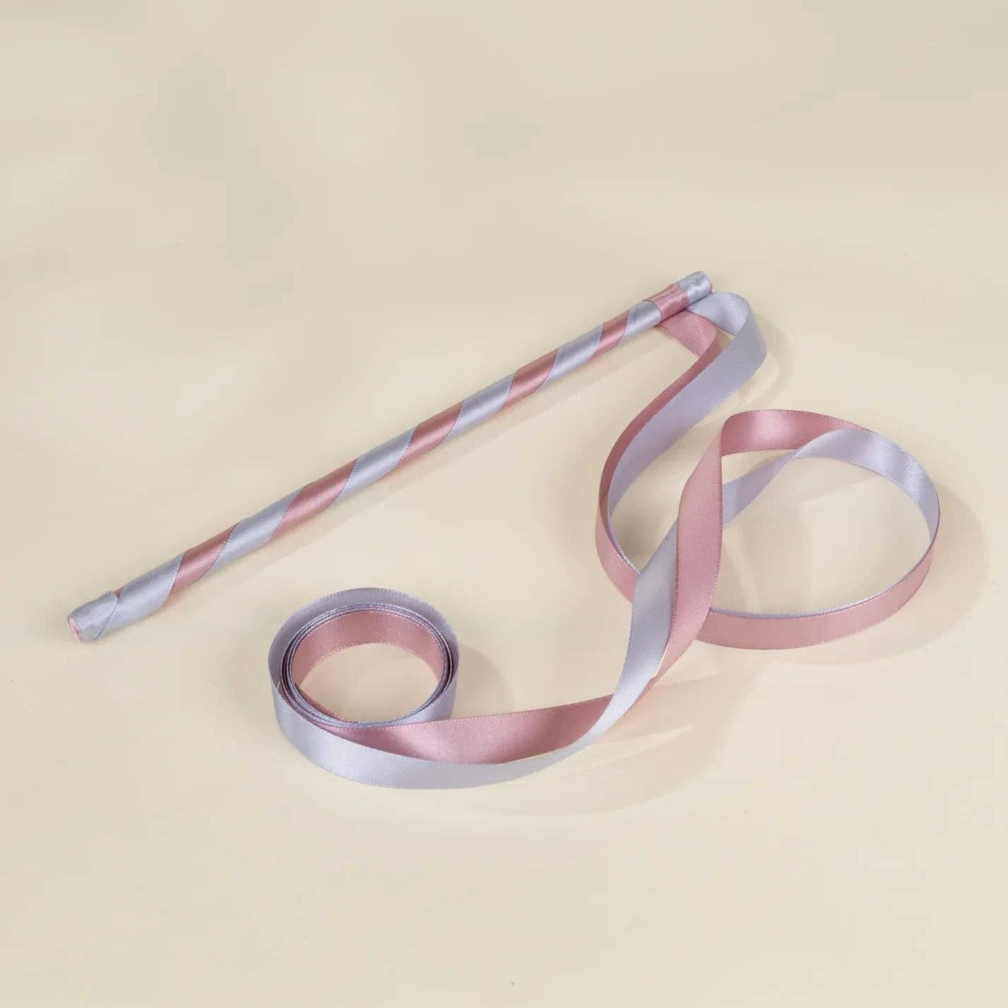 A pastel striped ribbon with alternating light pink and pale lavender-blue stripes, shown partially unrolled on a warm cream background.
