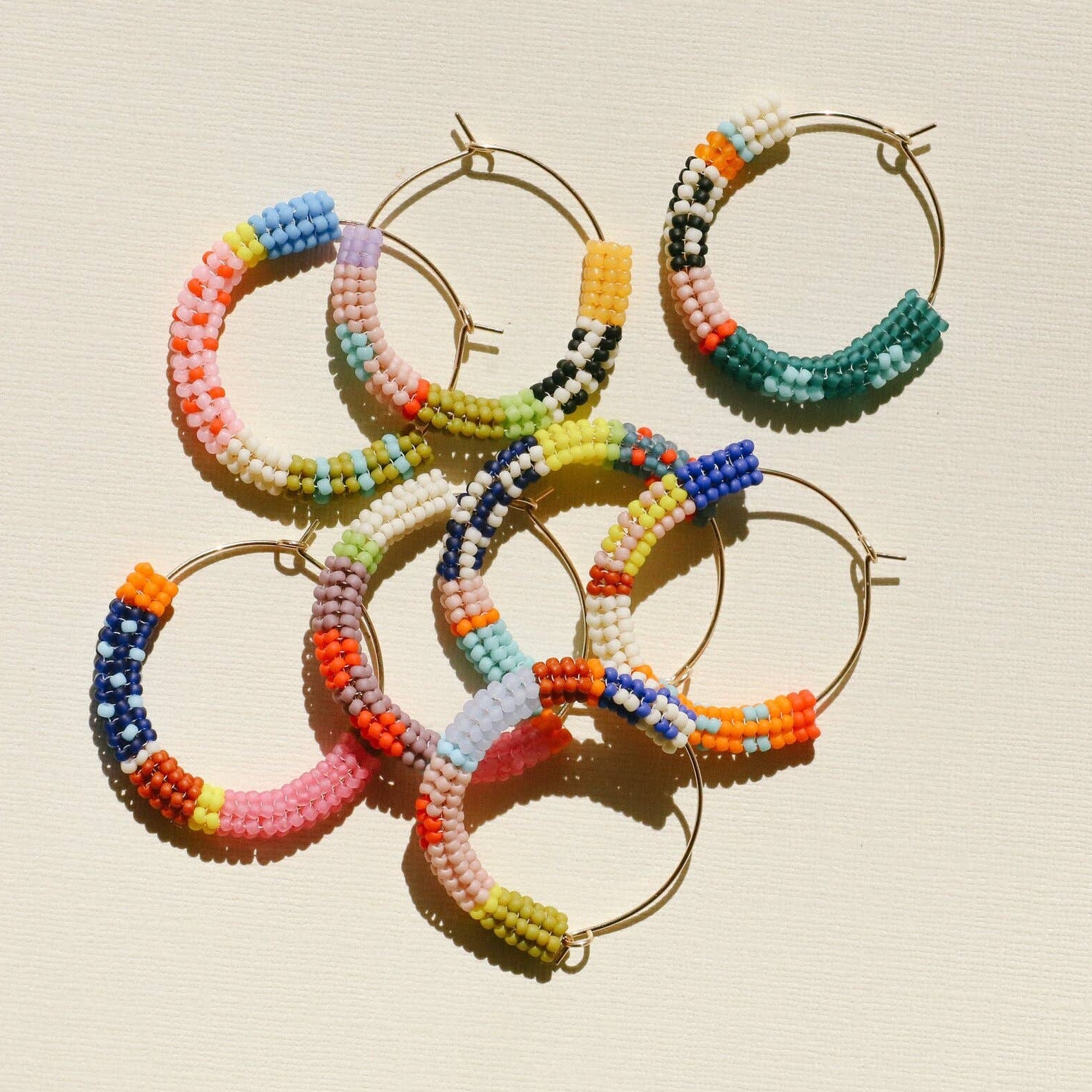 Colorful beaded hoop earrings on a beige background