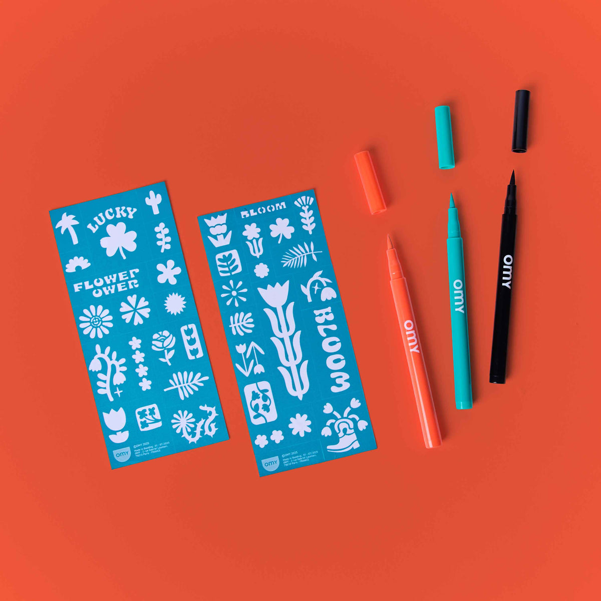 Two blue sticker sheets with floral designs and three markers on an orange background