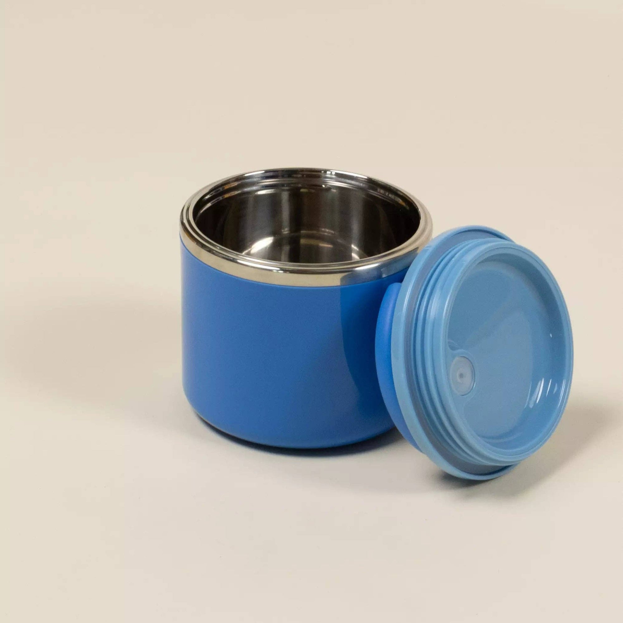 Blue thermos with silver interior on a beige background
