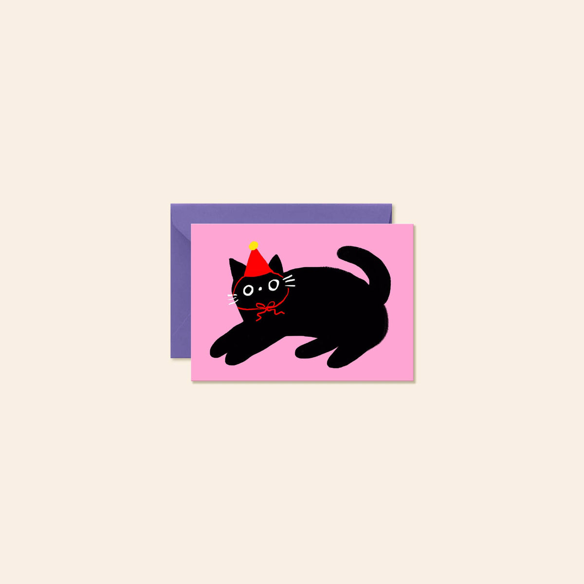A pink greeting card featuring a black cat wearing a red and yellow party hat, shown with a purple envelope behind it on a light beige background.
