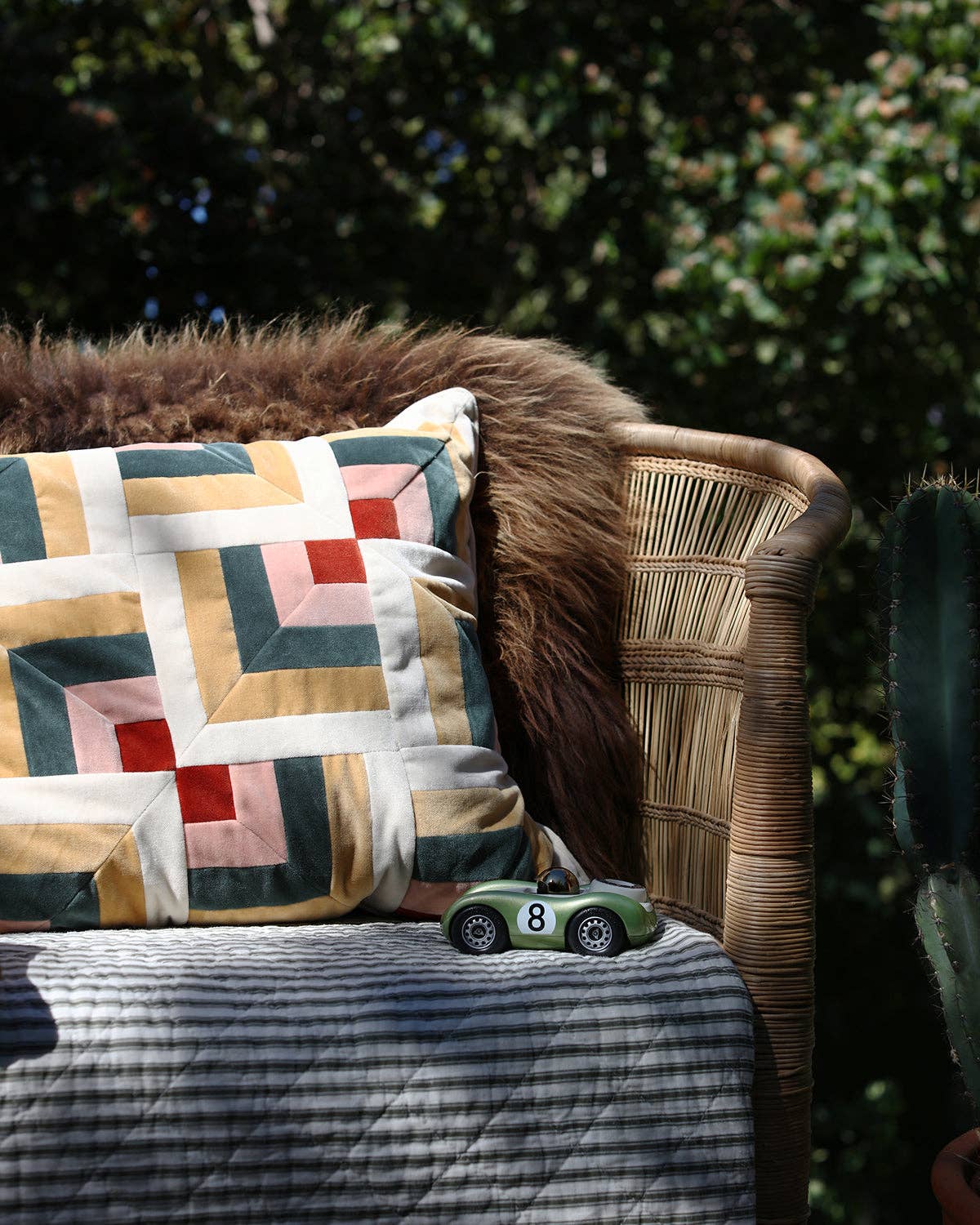 Decorative pillow with geometric pattern on a wicker chair outdoors.