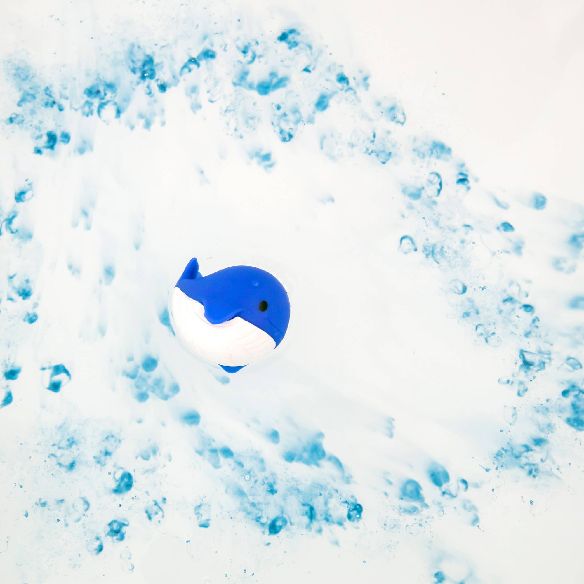 Blue whale toy surrounded by blue bubbles on a white background