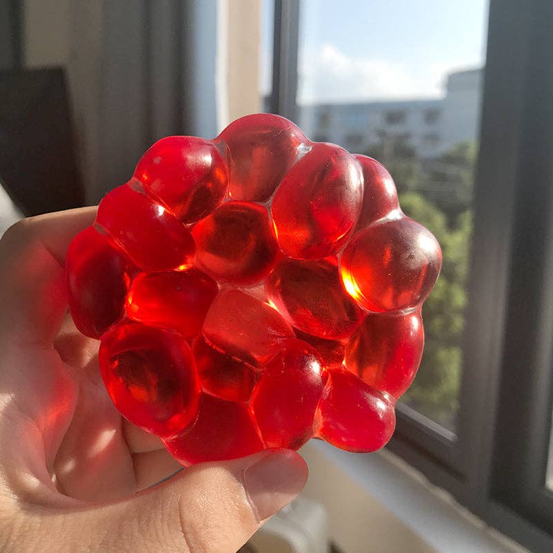 Red gel ball held in a hand with a window in the background