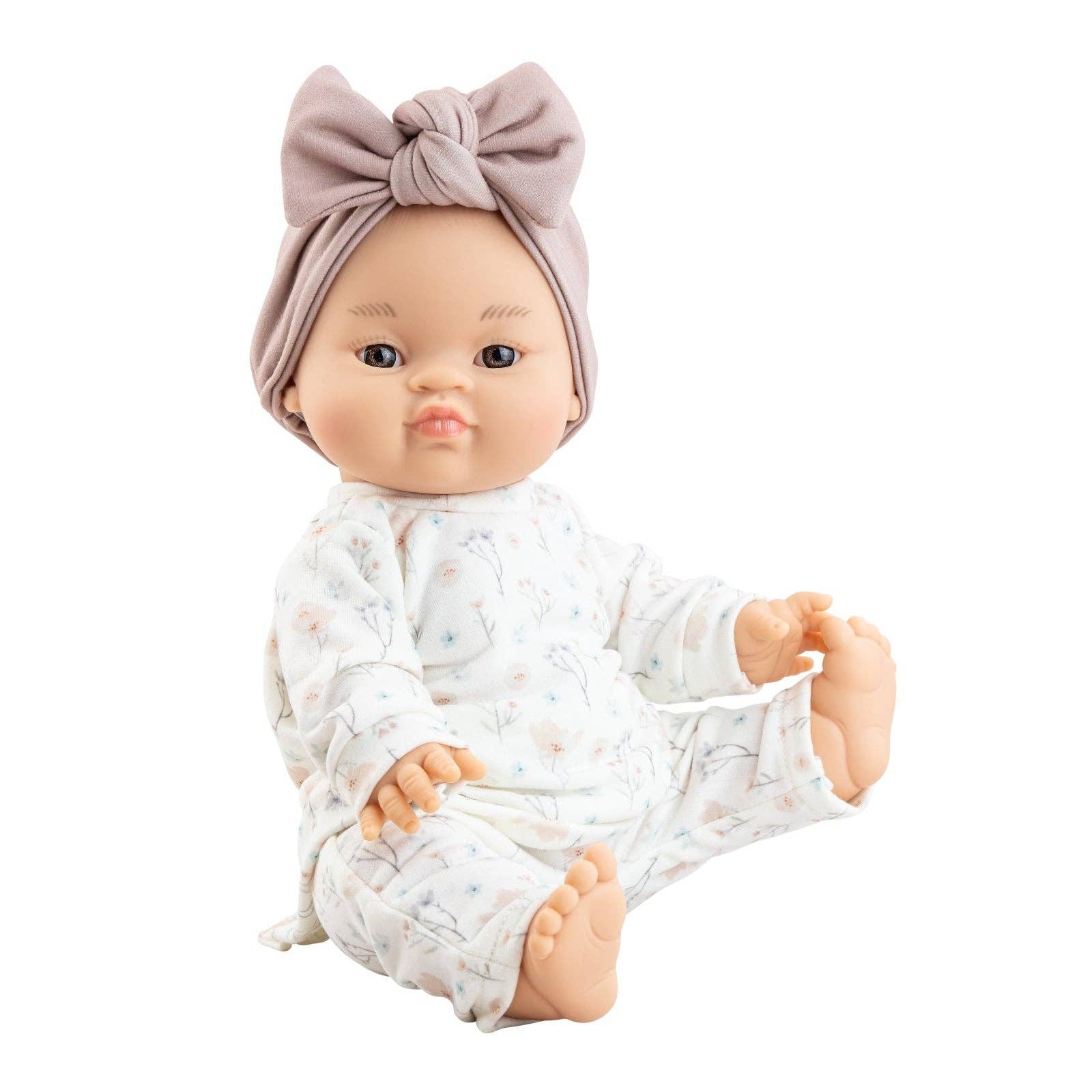 Baby doll wearing a white outfit with small patterns and a pink headband on a white background