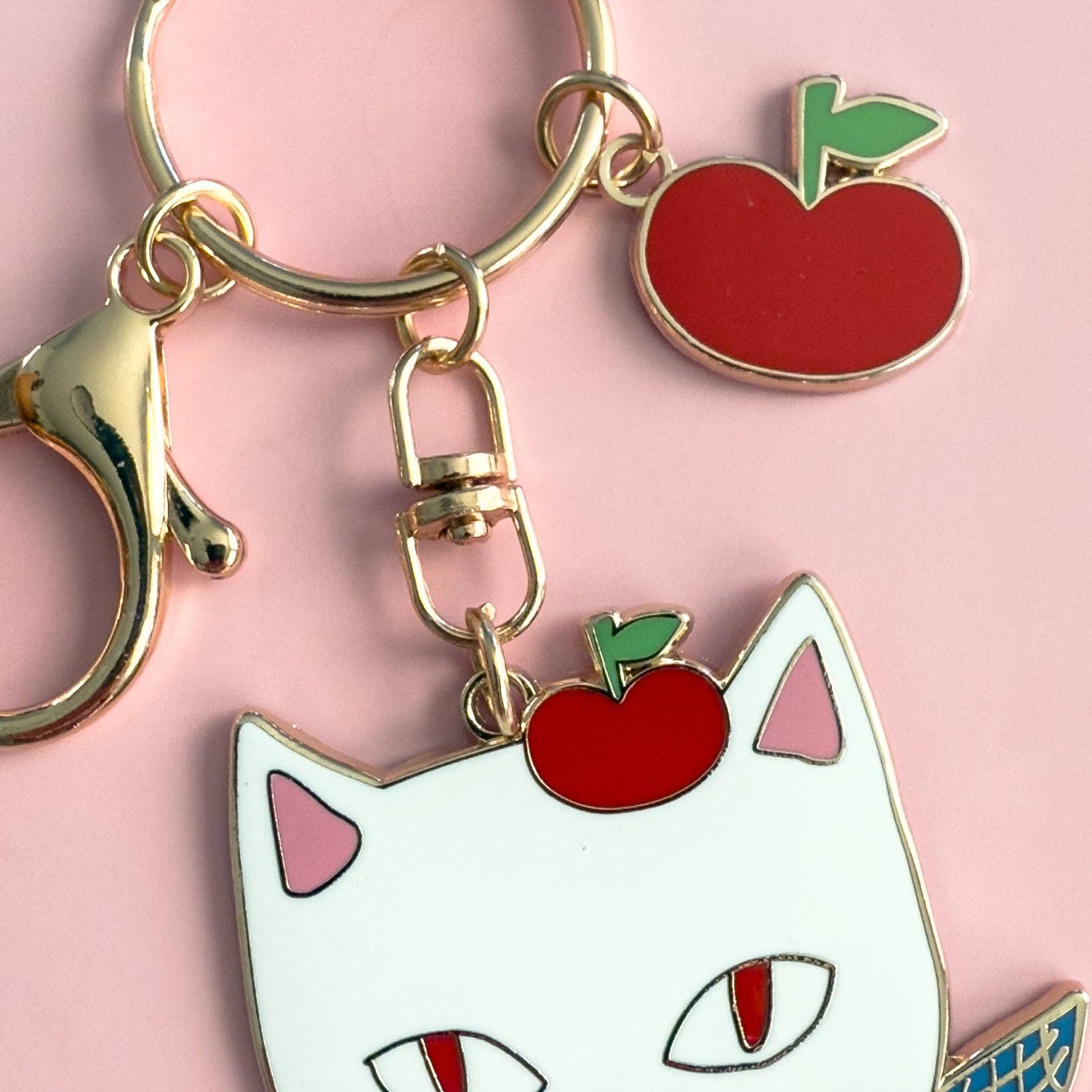 Keychain with cat face and apple charms on a pink background
