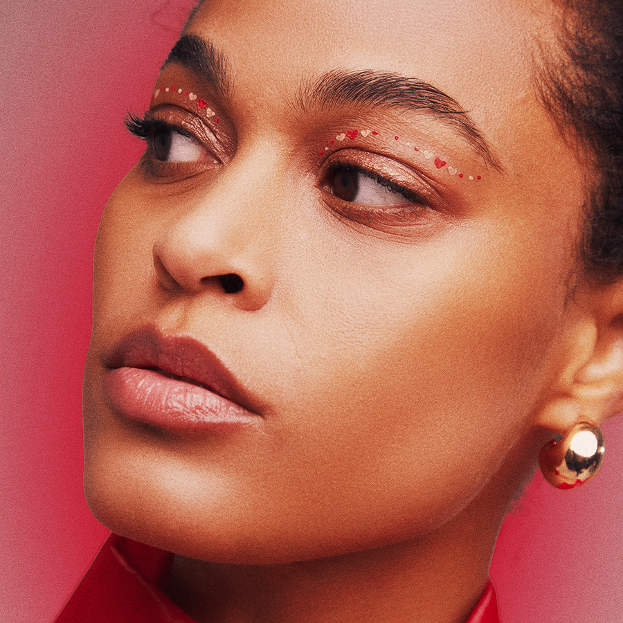 Close-up of a woman wearing gold earrings against a red background