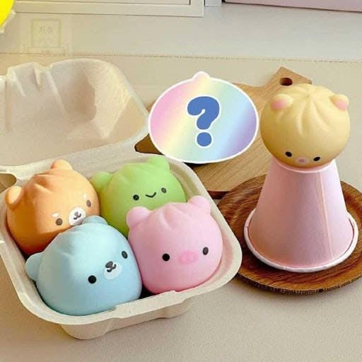 Set of colorful animal-shaped squishies in an egg carton with a question mark symbol.