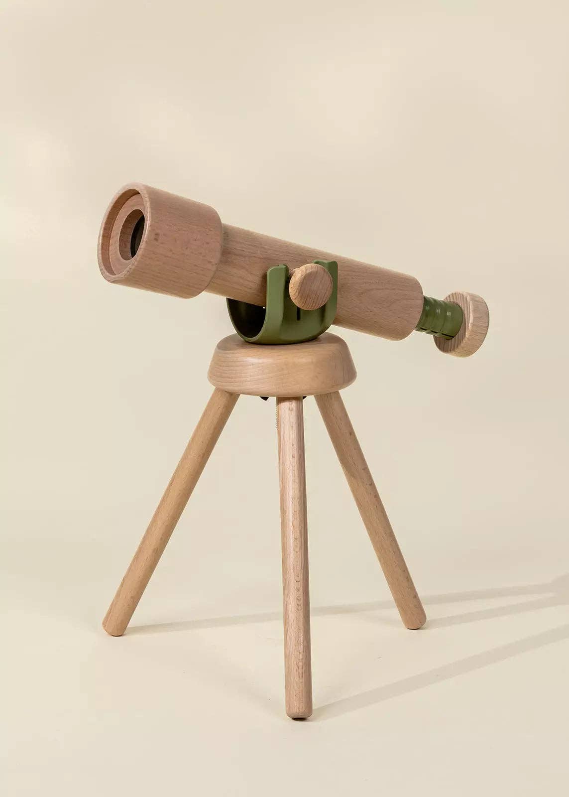 Wooden toy telescope on a tripod with a beige background