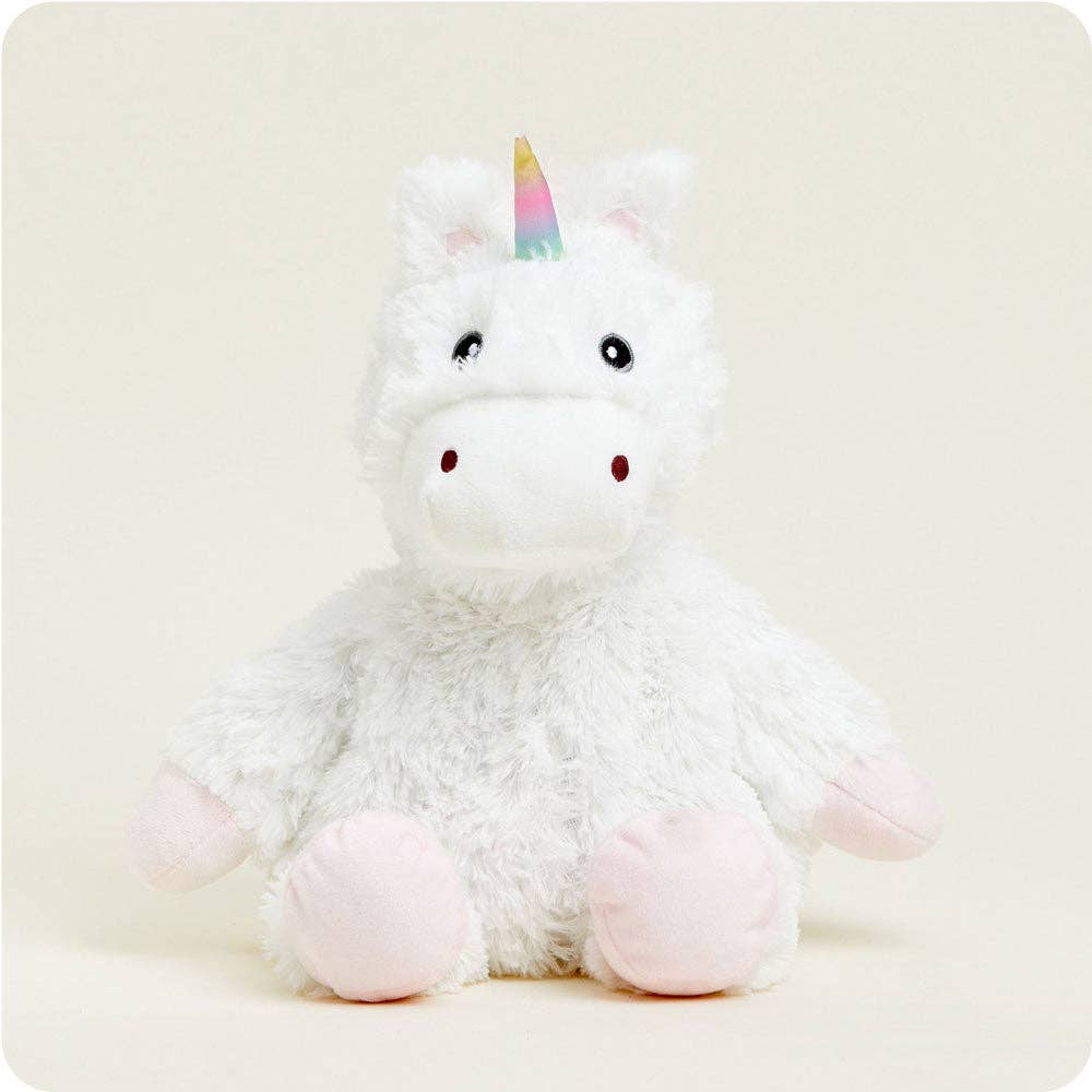 Plush unicorn toy with a rainbow horn on a light beige background