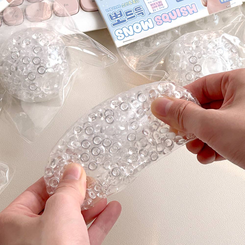 Clear bubble wrap sheet held by hands with packaging in the background