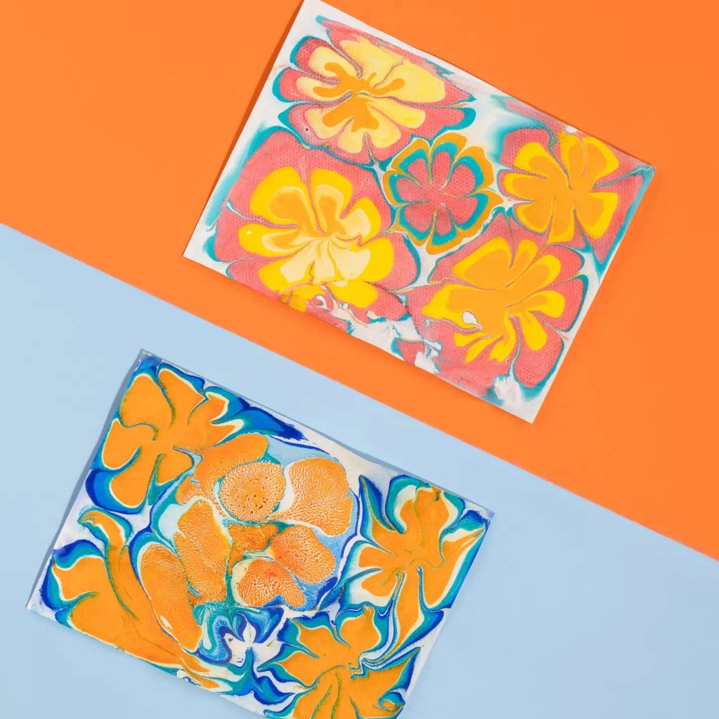 Two colorful floral glass coasters on a blue and orange background