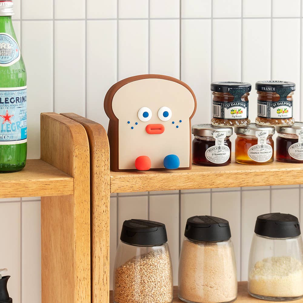 Wooden shelf with a bread-shaped mitt, bottles, and jars against a tiled wall.