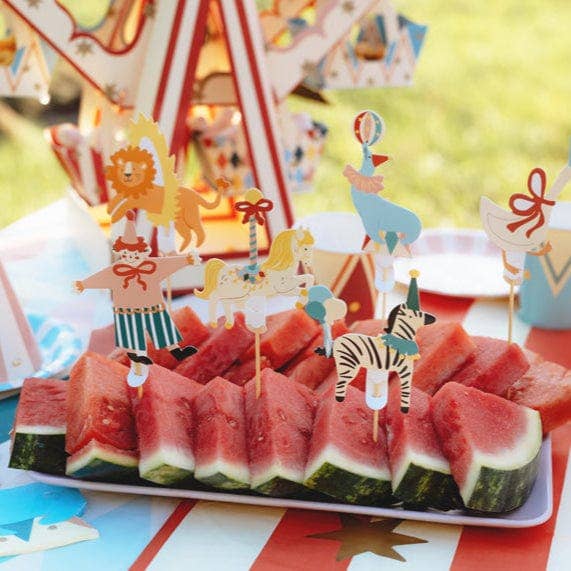 Watermelon slices with animal-themed skewers on a festive background