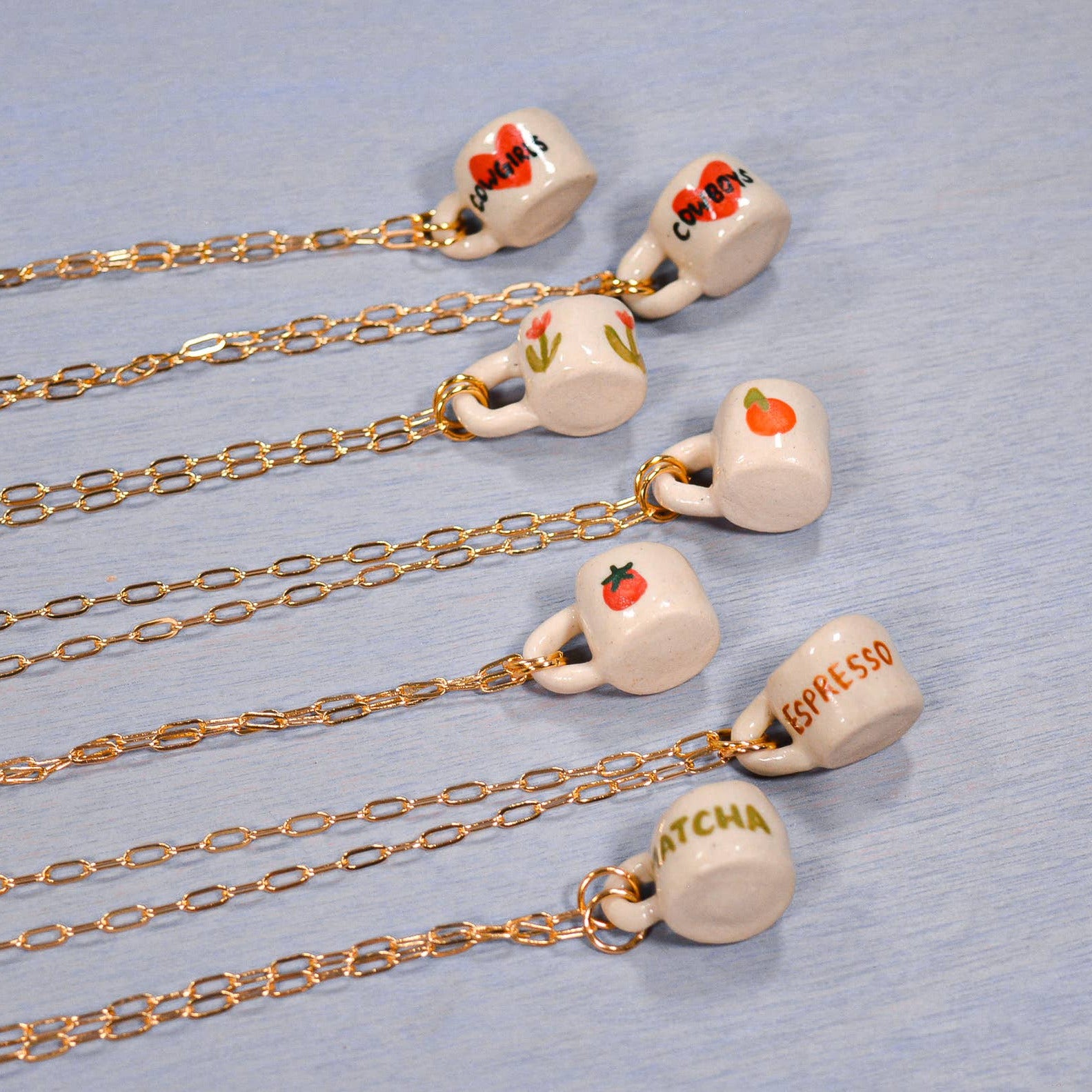 Necklaces with small ceramic cups on a light blue background