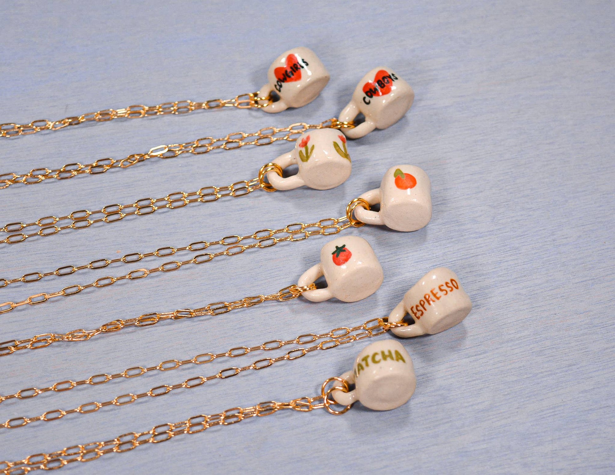 Necklaces with small ceramic cups on a light blue background