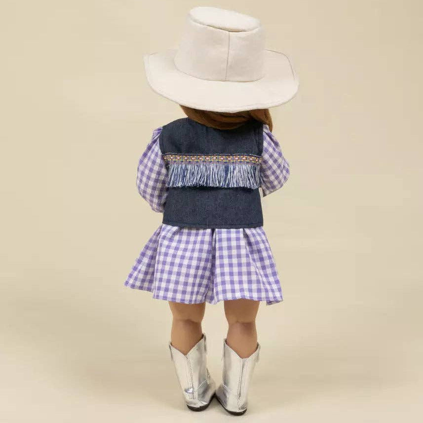 Child wearing a denim dress with plaid skirt, white cowboy hat, and silver boots on a beige background