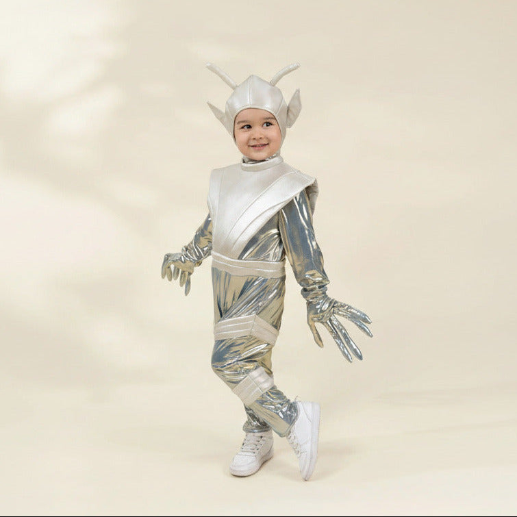 A child modeling a shiny silver and white futuristic alien or robot costume with a matching helmet, standing against a plain beige studio background.
