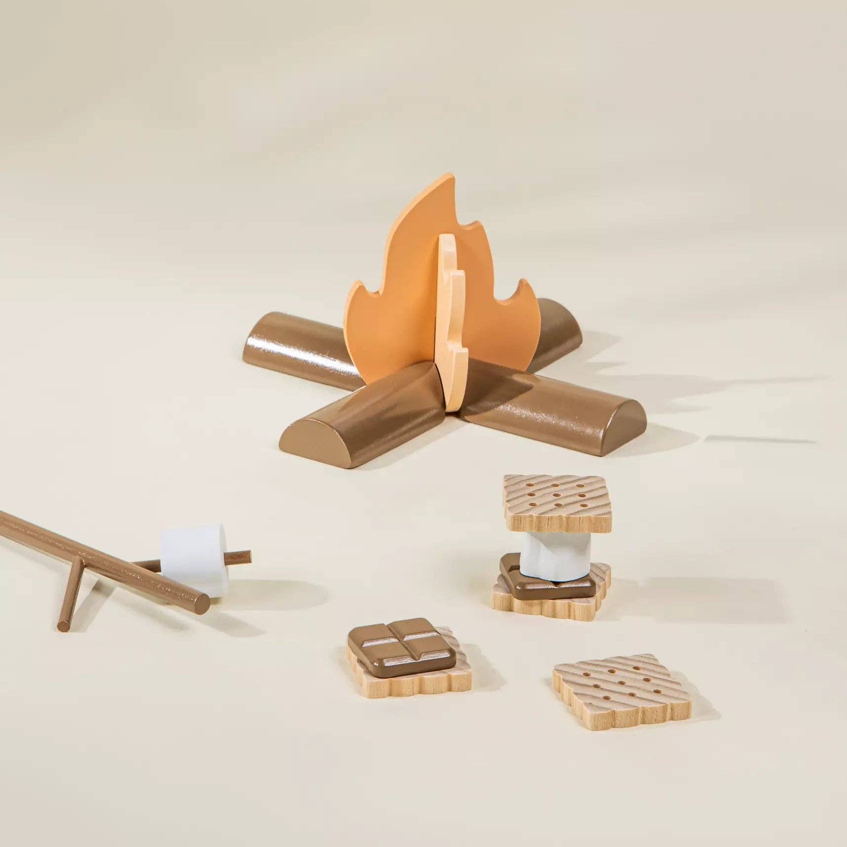 Wooden toy campfire with logs and a cooking stick on a beige background