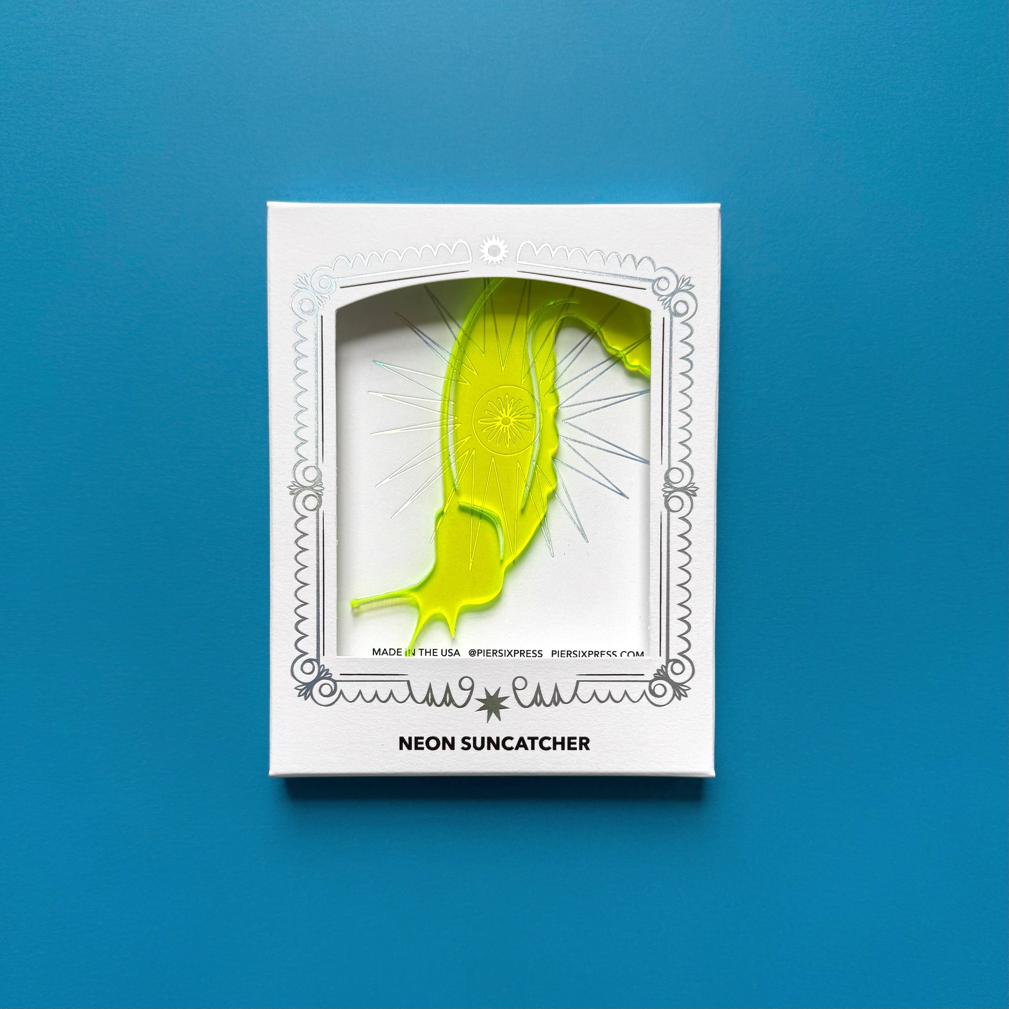 Neon suncatcher in a white box on a blue background