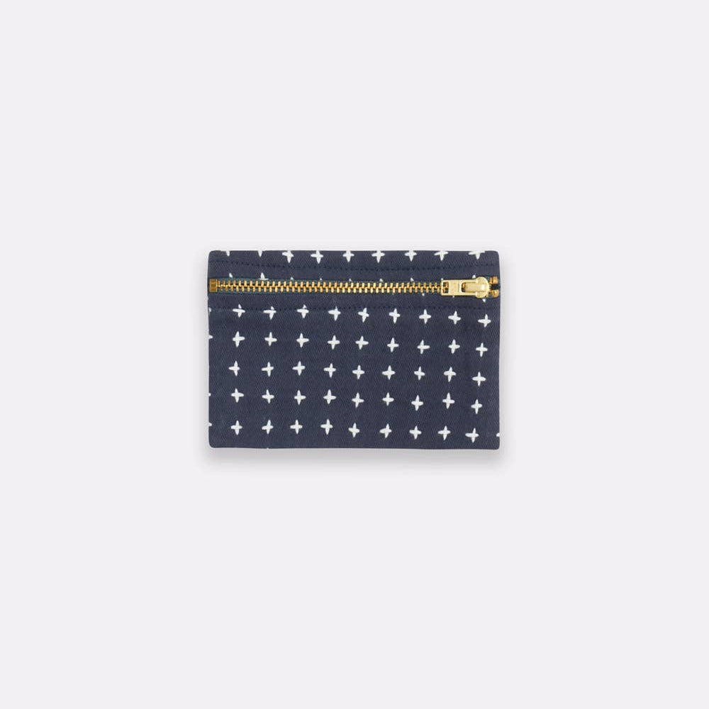 Navy pouch with white star pattern and gold zipper on a light gray background