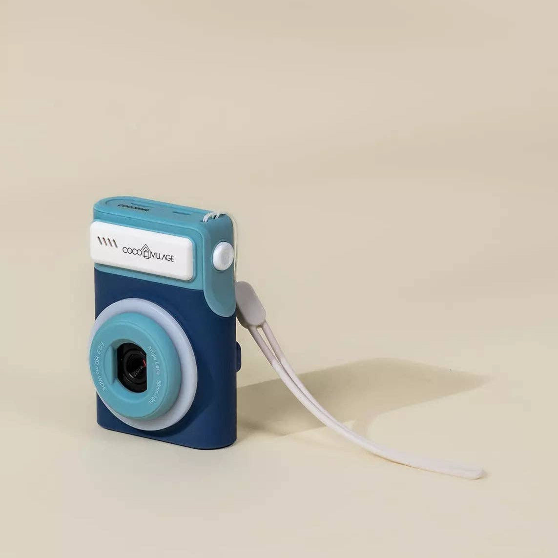 Small blue camera with a strap on a beige background