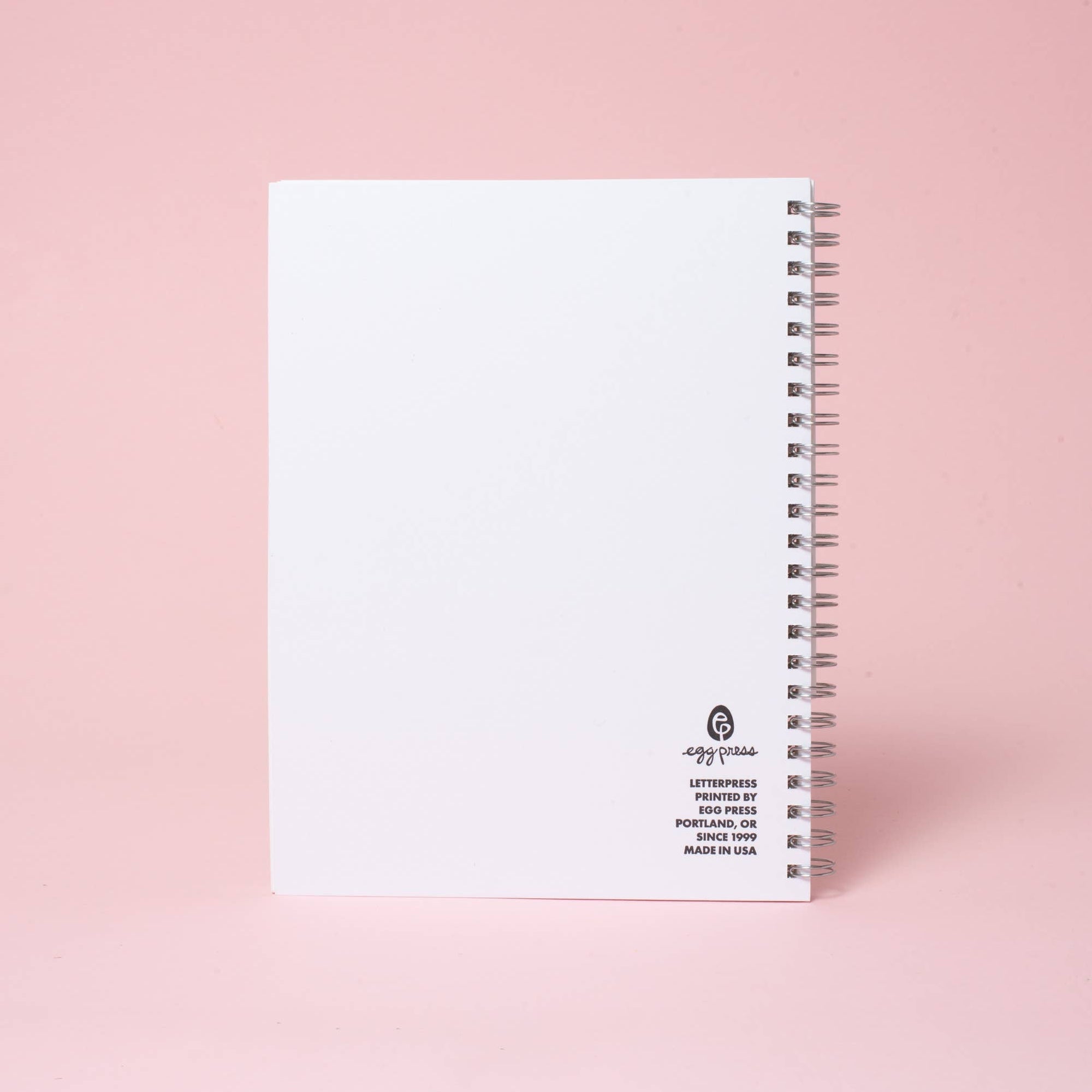 White notebook with black text on a pink background