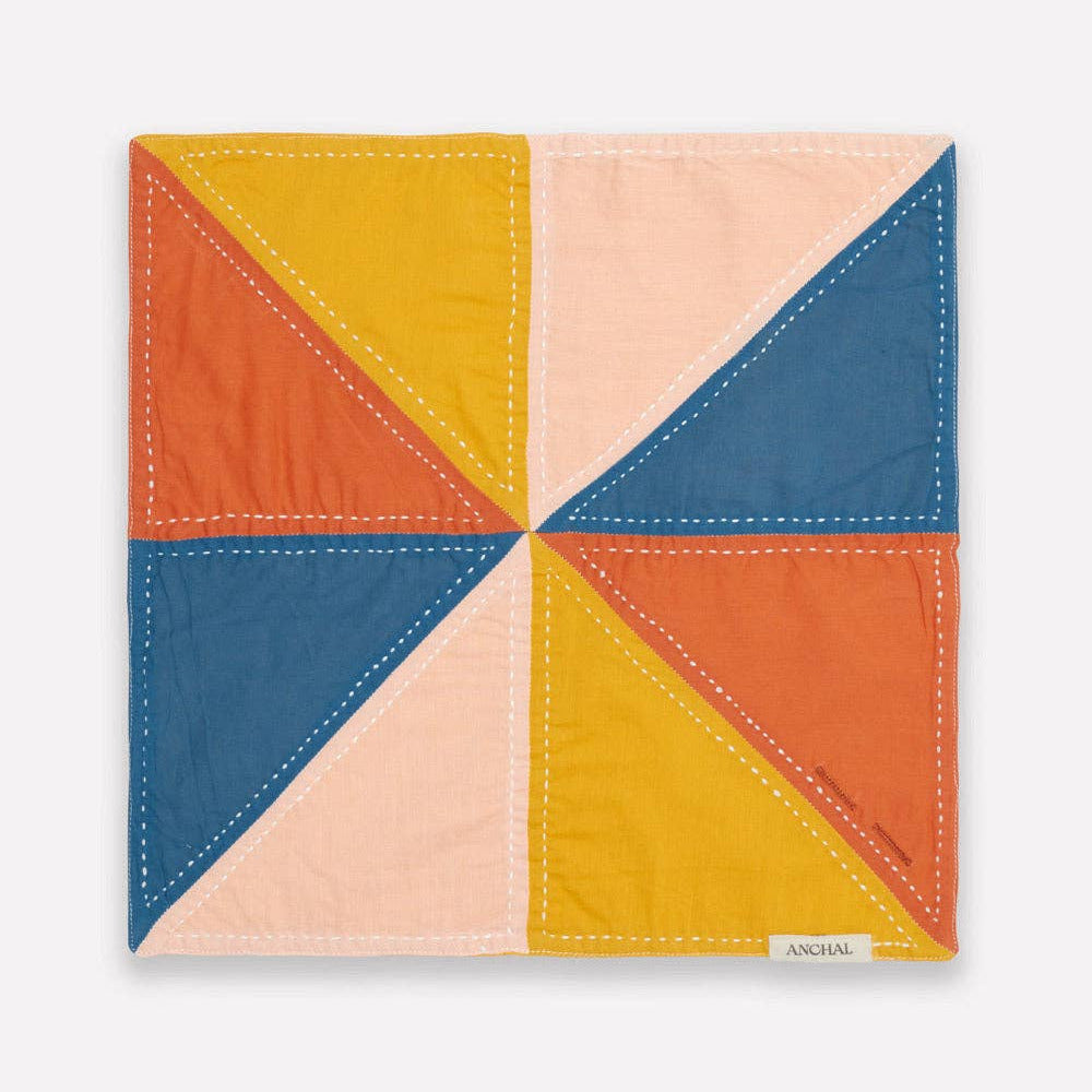 Colorful quilted square with geometric pattern on a white background