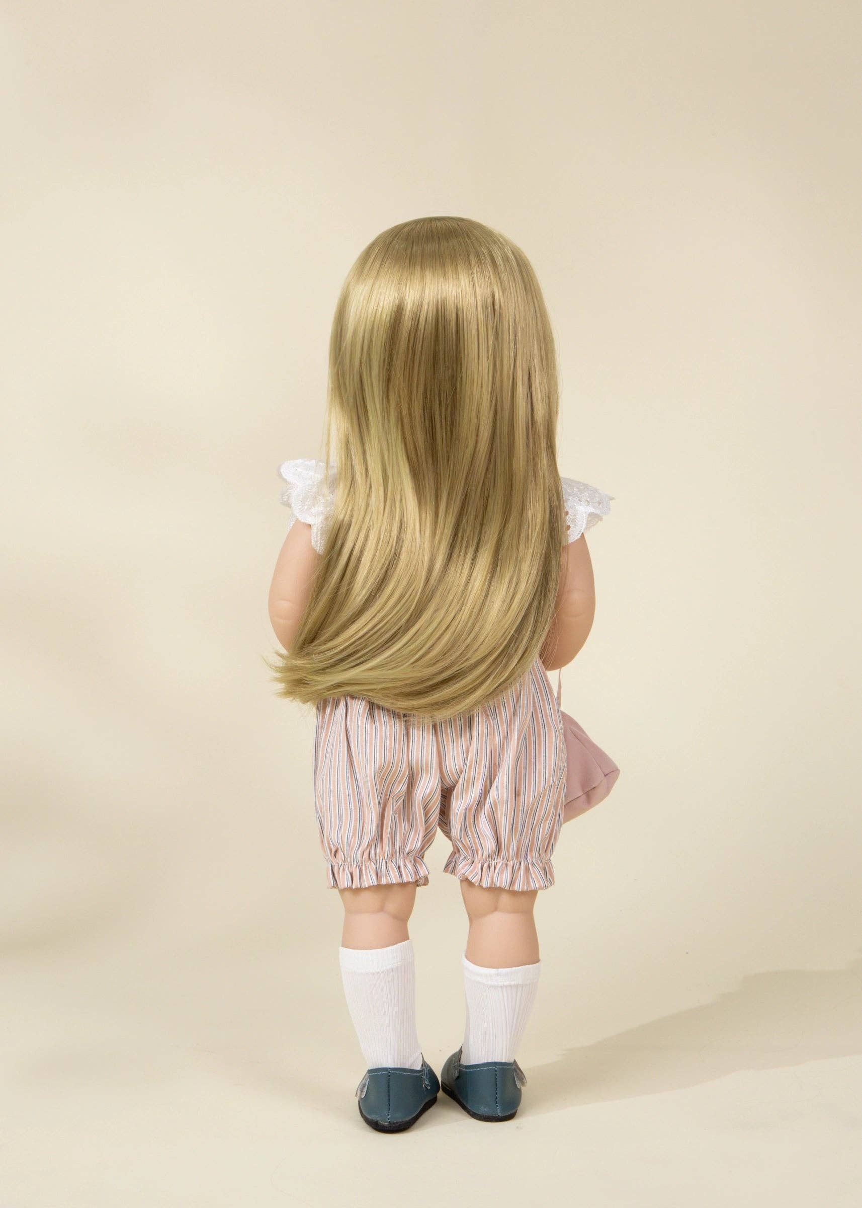 Child with long blonde hair wearing a pink outfit on a beige background