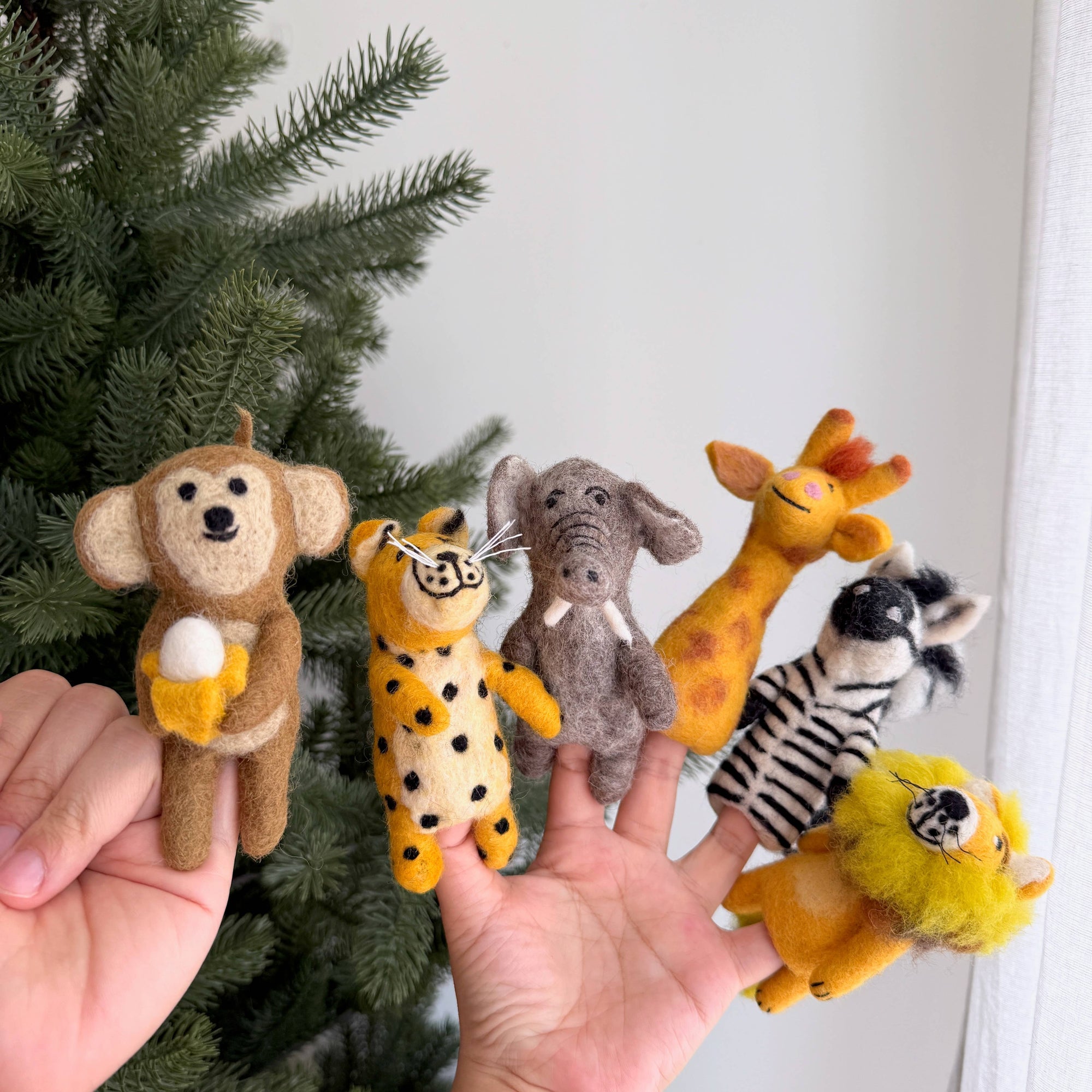 Set of finger puppets shaped like animals held by hands against a white background.