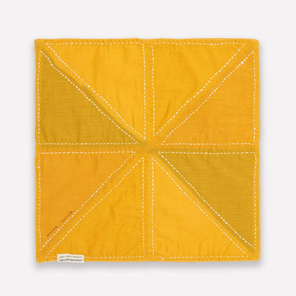 Yellow quilted square with white stitching on a light gray background