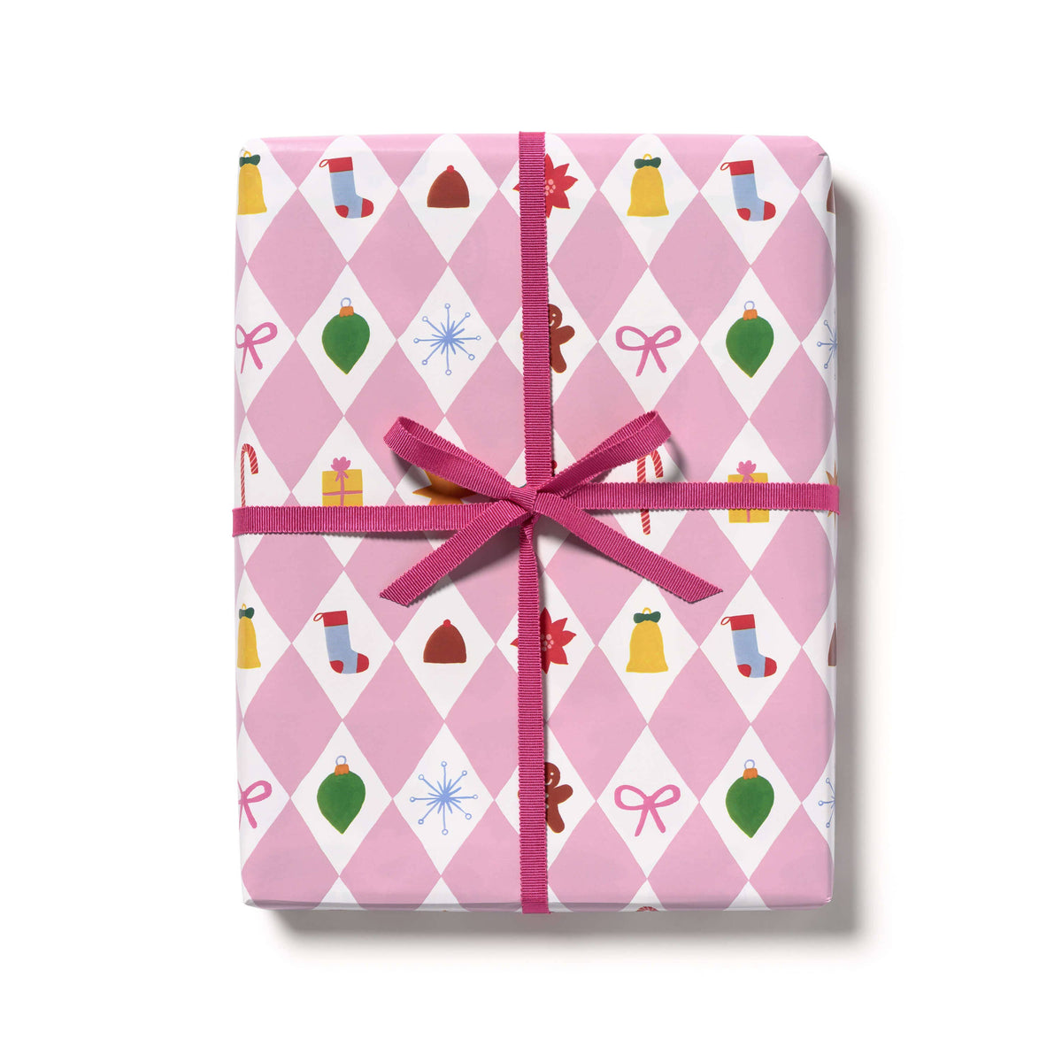 A rectangular gift box wrapped in pink and white argyle holiday paper with Christmas motifs, tied with a bright pink ribbon and bow, on a white background.