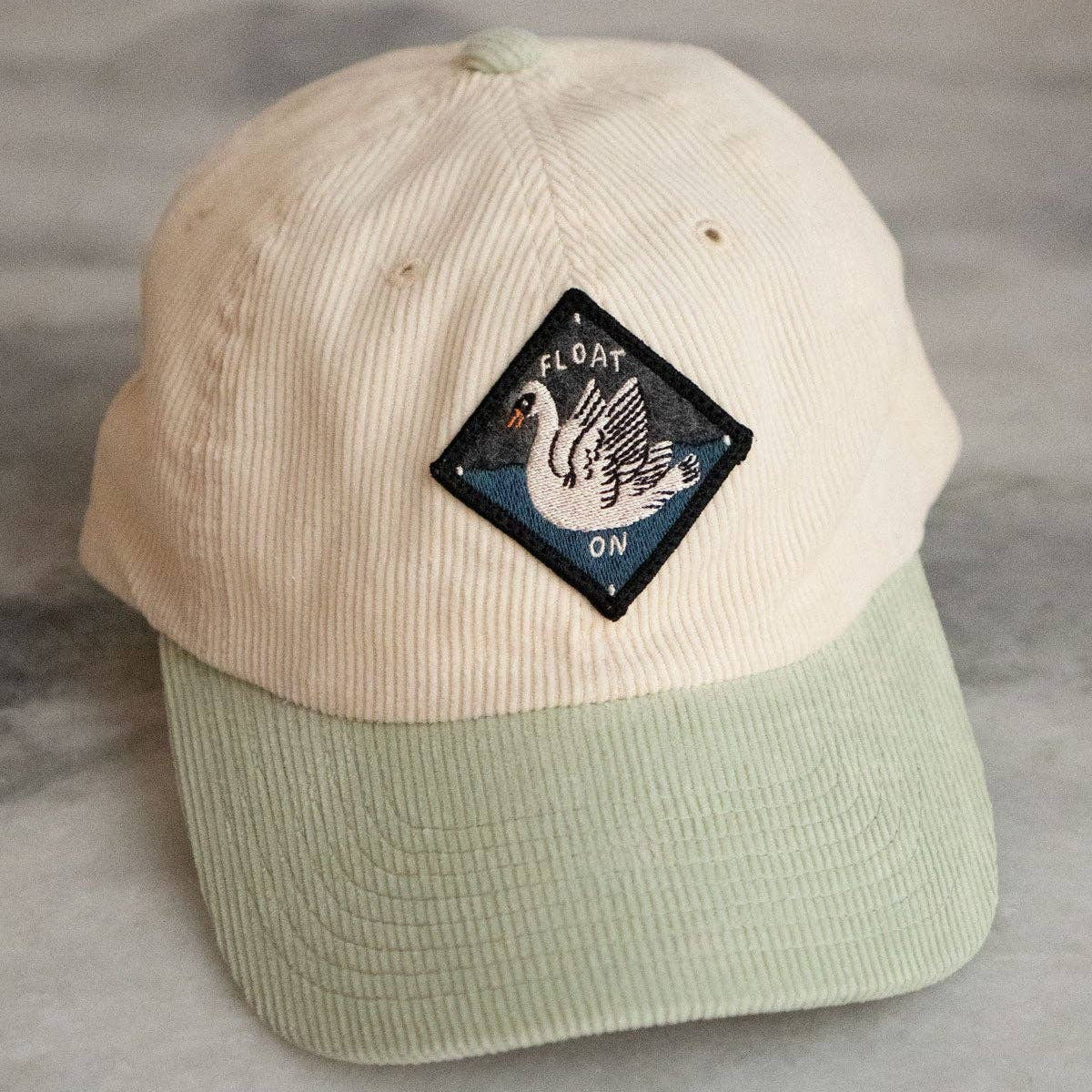 Beige and green cap with a patch on a gray surface