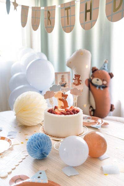 Birthday celebration setup with cake, balloons, and decorations on a table.