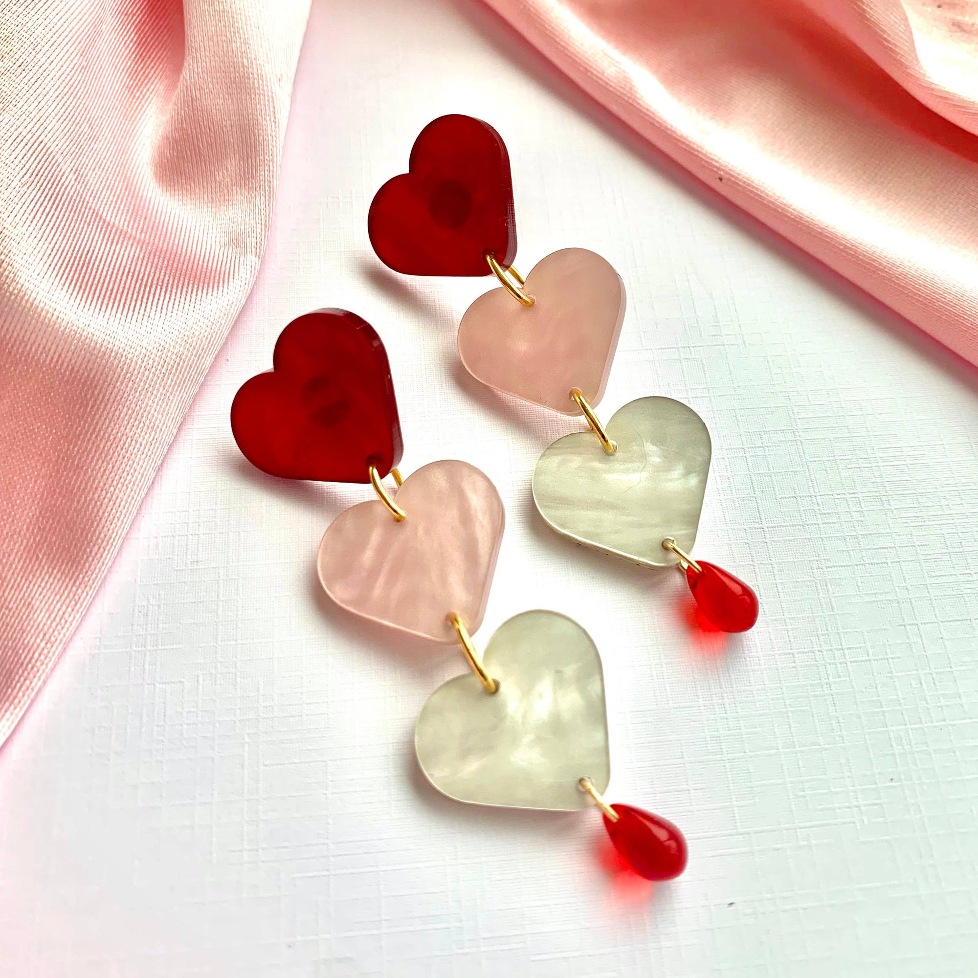 Heart-shaped earrings on a pink fabric background